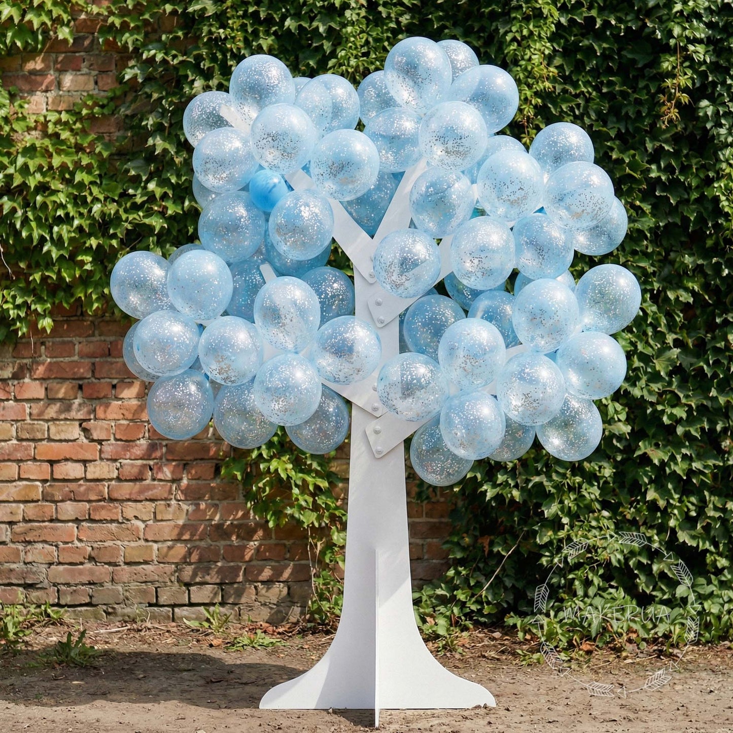 Balloon tree with blue balloons against a brick wall and green hedge