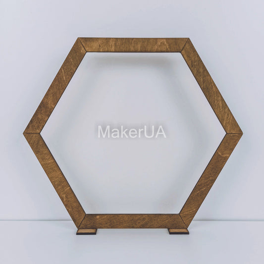 Large open hexagonal wooden arch with a natural brown wood finish. Rustic boho backdrop frame for outdoor wedding ceremonies and floral displays.