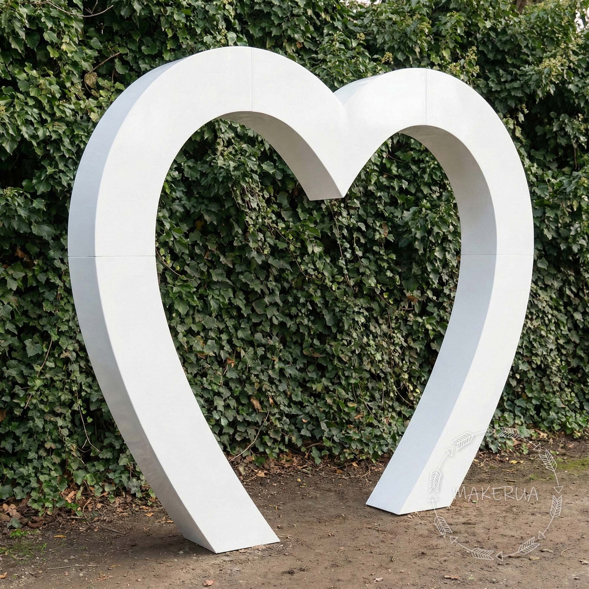 Large white 3D heart-shaped arch standing outdoors against a green ivy wall. Romantic solid backdrop frame for wedding ceremonies, Valentine's photo booths, and elegant event decor.