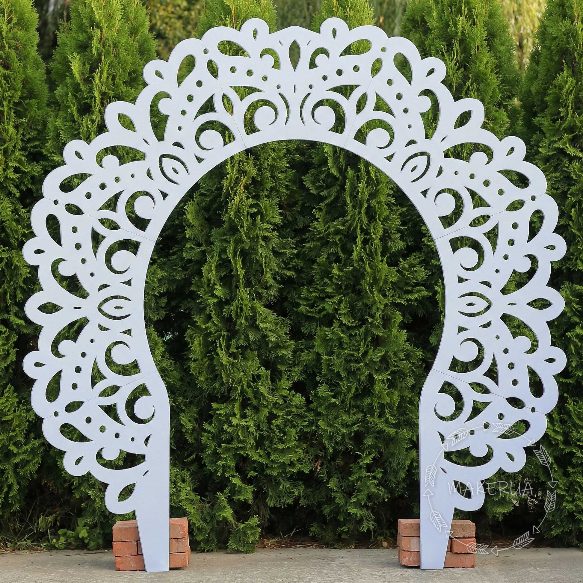 White wooden archway featuring an intricate cutout mandala pattern. Styled outdoors against green trees. Perfect boho chic backdrop for outdoor wedding ceremonies, spiritual events, and bohemian photo zones.