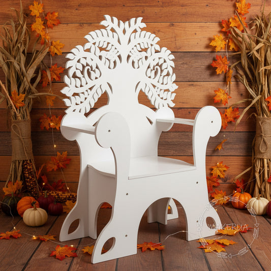 White wooden event chair featuring a Tree of Life cutout on the backrest, surrounded by autumn leaves and pumpkins. Fall festival and party photo prop.