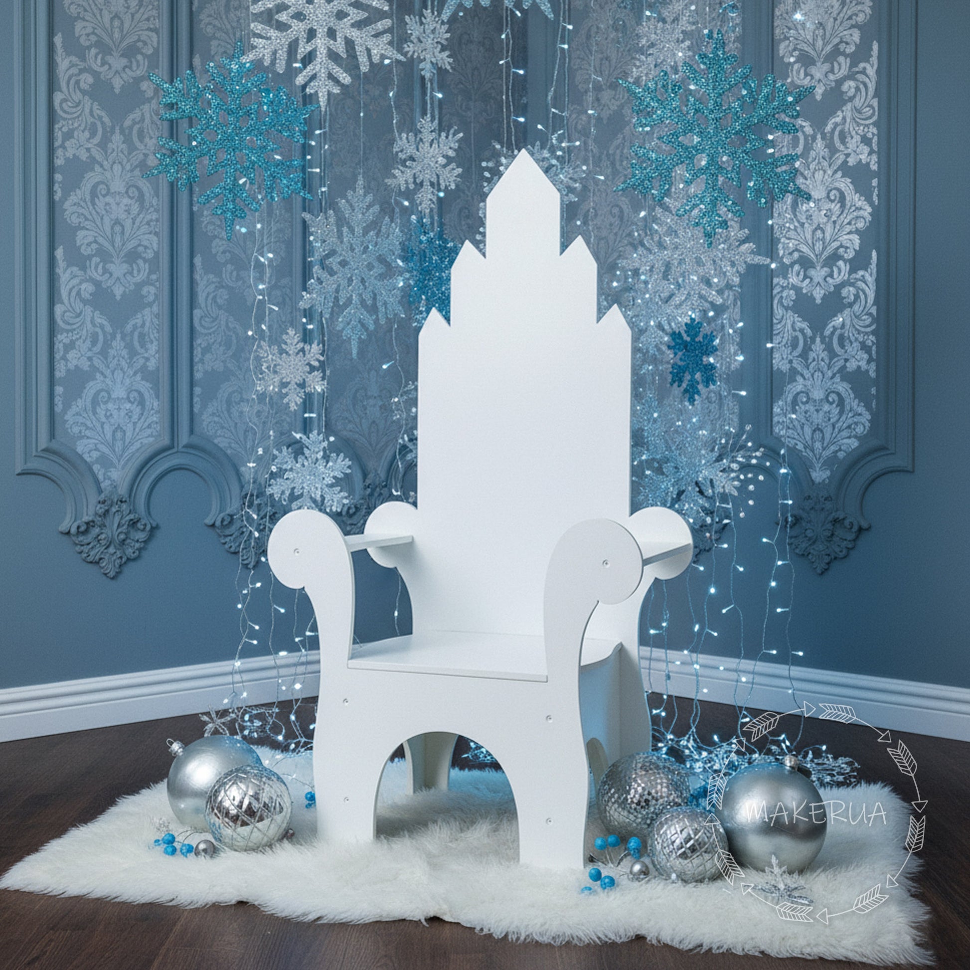 White wooden throne chair with a geometric castle tower backrest design, set in a winter photo zone with silver and blue ornaments. Perfect seating prop for Frozen themed birthday parties and holiday events.