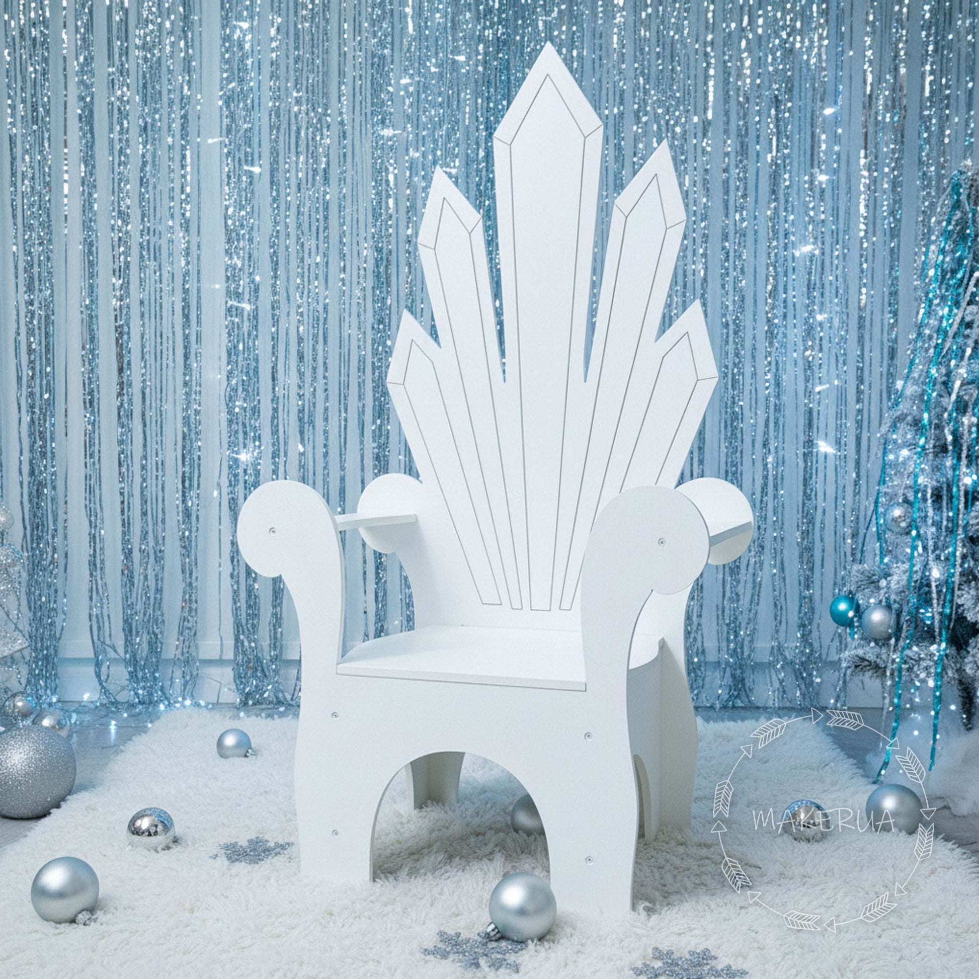 White throne chair in a snowy scene with silver ornaments and a sparkling blue curtain.