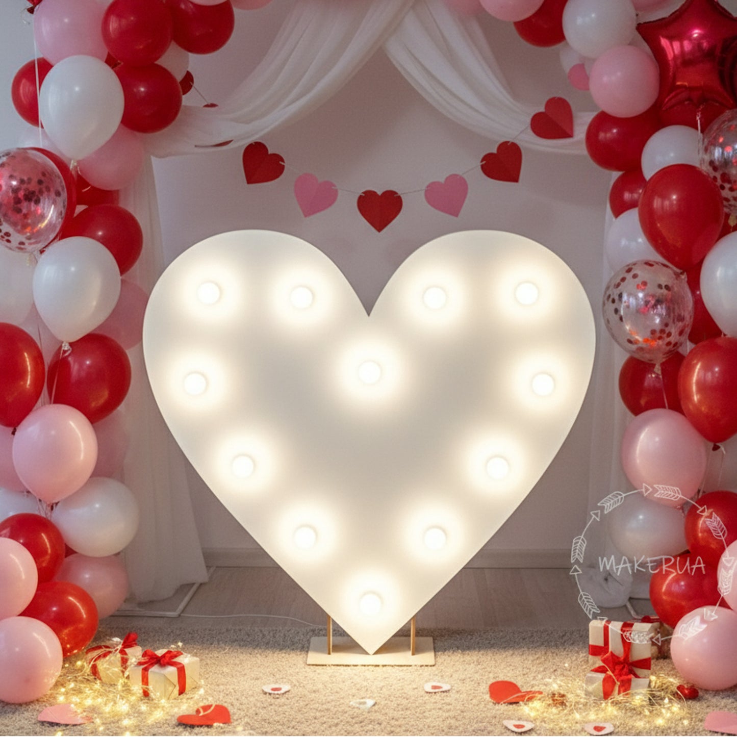 Heart-shaped light fixture surrounded by red, white, and pink balloons with a decorative arch.