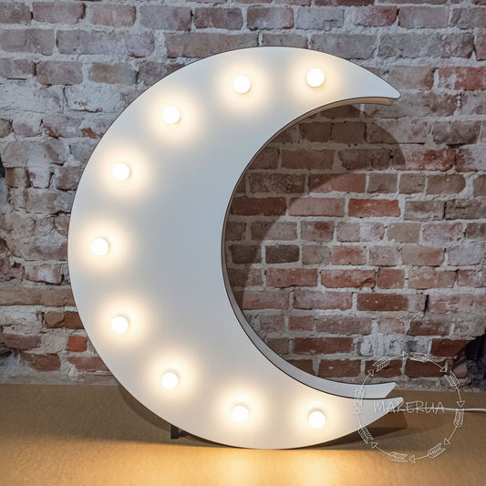 Decorative moon-shaped light with bulbs against a brick wall.